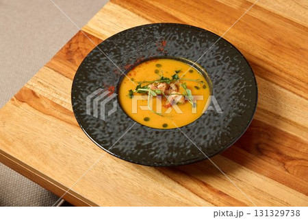 Indulge in a Deliciously Creamy Soup Served in a Modern Elegant Bowl on a Rustic Wooden Table Indulge in a Deliciously Creamy Soup Served in a Modern Elegant Bowl on a Rustic Wooden Table 131329738