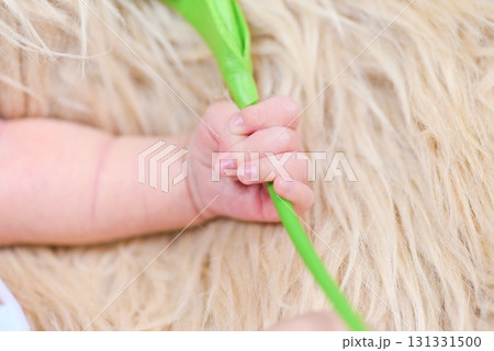 新生児の手とグリーン小物を握る瞬間 131331500