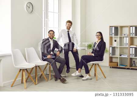 Group of business people of three looking at the camera and smiling at the workplace. 131333095