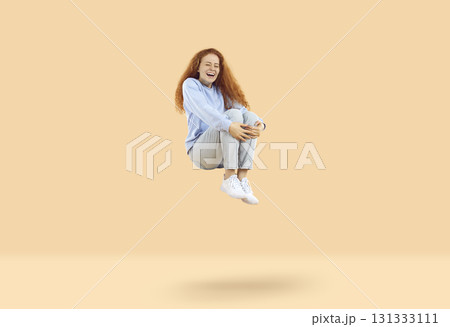 Cute funny woman laughing levitating in air as if falling and rising on light beige background. Cute funny woman laughing levitating in air as if falling and rising on light beige background. 131333111