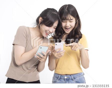 Happy Teenage girls laughing and using mobile phone Happy Teenage girls laughing and using mobile phone 131333135