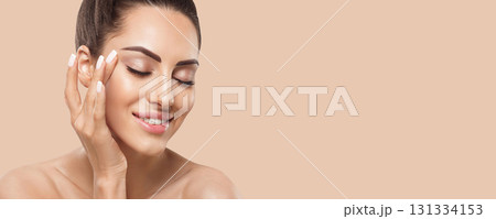 Beautiful smiling woman with healthy smooth facial clean skin applying cosmetic cream and touch own face. Model with Beauty face. Skin care Moisturizer Facial treatment. Cosmetology. Spa. Beautiful smiling woman with healthy smooth facial clean skin applying cosmetic cream and touch own face. Model with Beauty face. Skin care Moisturizer Facial treatment. Cosmetology. Spa. 131334153