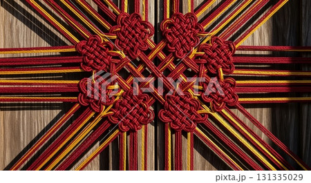 Traditional Chinese red and gold decorative knotwork with intricate endless knot pattern radiating from center on wooden background Traditional Chinese red and gold decorative knotwork with intricate endless knot pattern radiating from center on wooden background 131335029