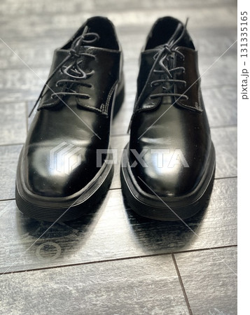 Black leather shoes on wooden floor, reflective surface creates elegant footwear background Black leather shoes on wooden floor, reflective surface creates elegant footwear background 131335165