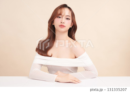A beautiful young Asian woman with clean, fresh skin against a beige background. Skincare, facial treatment, cosmetology, beauty, and spa. An elegant portrait of an Asian woman. 131335207