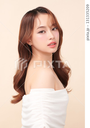 A beautiful young Asian woman with clean, fresh skin against a beige background. Skincare, facial treatment, cosmetology, beauty, and spa. An elegant portrait of an Asian woman. 131335209