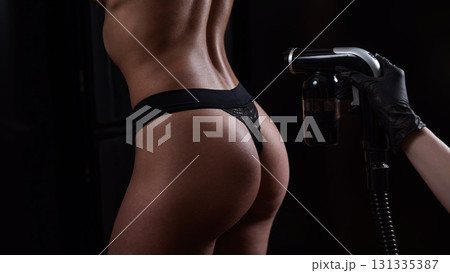 The master applies tinting paint on the back of a woman. Instant tanning treatment. The master applies tinting paint on the back of a woman. Instant tanning treatment. 131335387