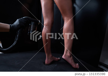 The master applies tinting paint to the woman's legs. Instant tanning procedure 131335390