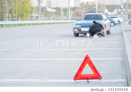 Warning triangle. Man disconnects tow rope from car. Warning triangle. Man disconnects tow rope from car. 131335419