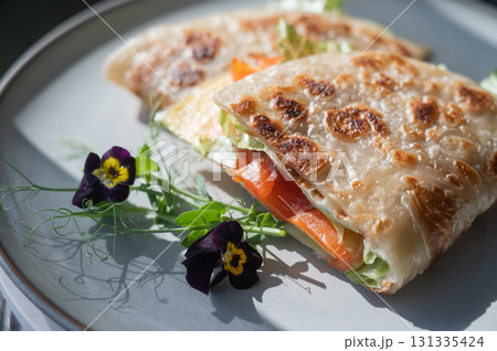 A flatbread stuffed with fish and cheese served in a cafe. Quesadilla. 131335424