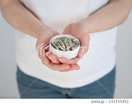 A woman holds a jar of chewing tobacco.  131335452