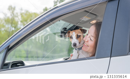 Caucasian woman looking out of car window with dog.  131335614