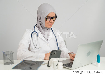Female doctor in hijab talking to patient via video link on laptop. Female doctor in hijab talking to patient via video link on laptop. 131335628