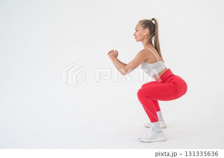 Young woman doing squats on white background. Vertical video. Young woman doing squats on white background. Vertical video. 131335636