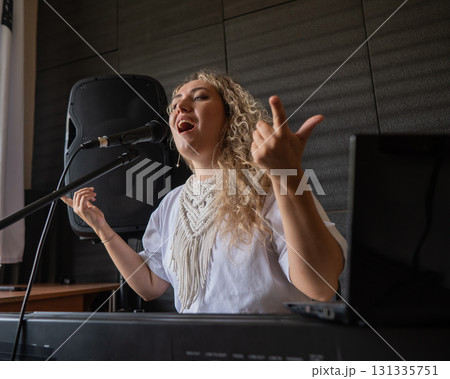 Caucasian woman singing into microphone and playing synthesizer.  131335751