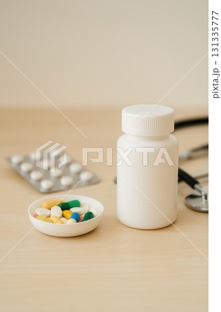 Colorful assortment of tablets and capsules in a white bowl beside a plain medicine bottle on a 131335777