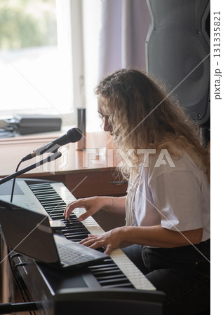 Caucasian woman singing into microphone and playing synthesizer. Online lesson on laptop. Caucasian woman singing into microphone and playing synthesizer. Online lesson on laptop. 131335821