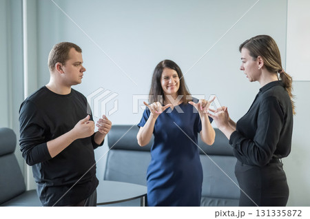 Caucasian woman teaching sign language to man and woman.  131335872
