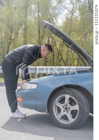 Caucasian man looking under the hood of his car. Caucasian man looking under the hood of his car. 131335874