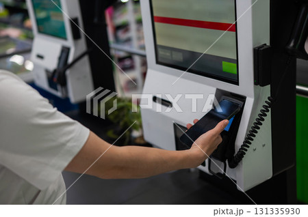 A woman pays using her smartphone at a self-checkout.  131335930