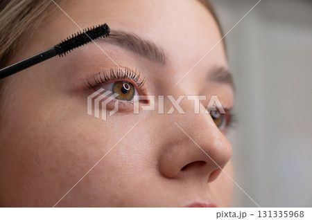 Young Woman Applying Mascara to Enhance Eyelashes.  131335968