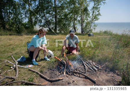 Caucasian couple roasting sausages over a fire. Caucasian couple roasting sausages over a fire. 131335985