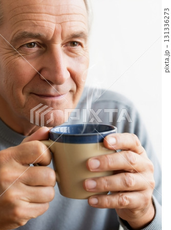 Senior man smiling while holding a mug of hot coffee or tea. Close-up portrait of a happy older person relaxing. Retirement lifestyle concept Senior man smiling while holding a mug of hot coffee or tea. Close-up portrait of a happy older person relaxing. Retirement lifestyle concept 131336273