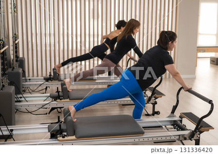 Three Asian women doing Pilates on a reformer. Three Asian women doing Pilates on a reformer. 131336420
