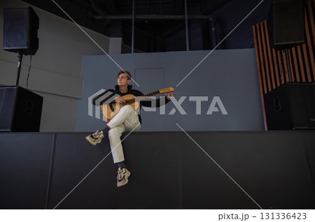 Caucasian man playing guitar while sitting on stage. Caucasian man playing guitar while sitting on stage. 131336423