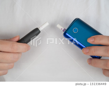 A woman compares two different tobacco heating systems. Electronic cigarette. 131336449