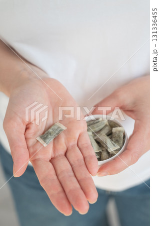 A woman holds a jar of chewing tobacco.  131336455