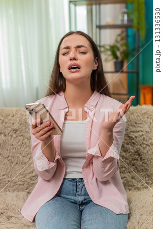 Young woman frowning at smartphone after contest loss shows sad reaction and very strong frustration 131336530