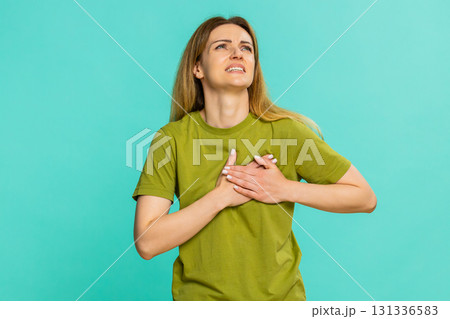 Adult woman sighing deeply placing hand on chest showing emotional exhaustion sudden pain in heart Adult woman sighing deeply placing hand on chest showing emotional exhaustion sudden pain in heart 131336583