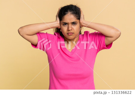Indian woman abruptly covers ears with hands, expressing discomfort from loud annoying sound noise Indian woman abruptly covers ears with hands, expressing discomfort from loud annoying sound noise 131336622