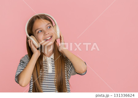 Child girl kid happily dances in wireless headphones enjoying favorite music smiling brightly 131336624