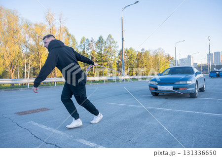 Caucasian man pulling a car with a rope.  131336650