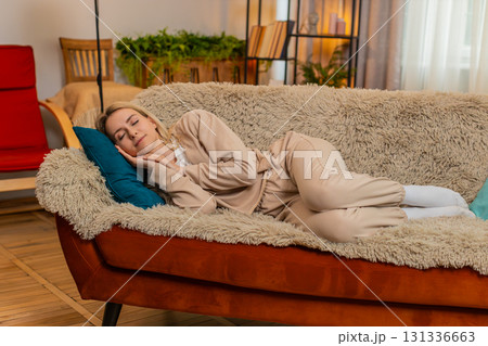 Adult woman falling asleep on sofa at home after work, showing tiredness peaceful emotional relief 131336663