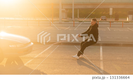 Caucasian man pulling a car with a rope. Caucasian man pulling a car with a rope. 131336664