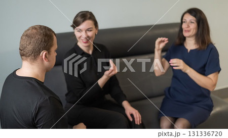 A man and two women are talking in Russian sign language.  131336720