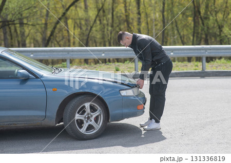 Caucasian man looking under the hood of his car. Caucasian man looking under the hood of his car. 131336819