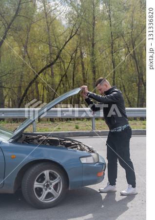 Caucasian man looking under the hood of his car.  131336820