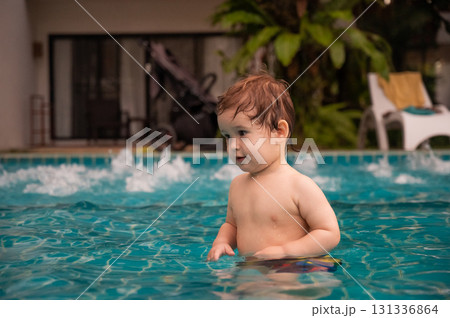 Caucasian one year old boy playing ball in swimming pool. Caucasian one year old boy playing ball in swimming pool. 131336864