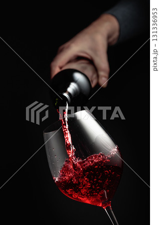 Pouring red wine in a glass goblet. 131336953