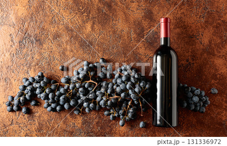 Blue grapes and bottle of red wine on a brown vintage background. Blue grapes and bottle of red wine on a brown vintage background. 131336972