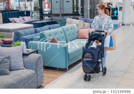 A Caucasian woman is shopping with her Jack Russell Terrier dog in a stroller in a shopping mall. 131336986