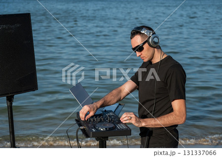 Caucasian man works as a DJ on the beach. Caucasian man works as a DJ on the beach. 131337066
