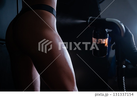 The master applies tinting paint to the woman's legs. Instant tanning procedure The master applies tinting paint to the woman's legs. Instant tanning procedure 131337154