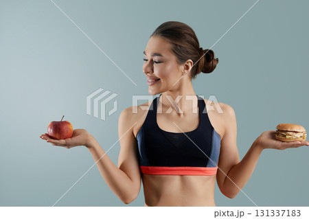 Woman making choice between apple and hamburger. Dieting concept. Healthy Eating, 131337183