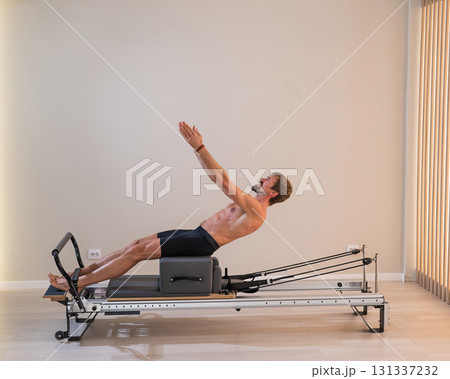 A man doing Pilates on a reformer.  131337232
