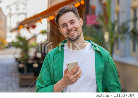 Man using smartphone typing text messages browsing internet, finishing work, looking at camera 131337304